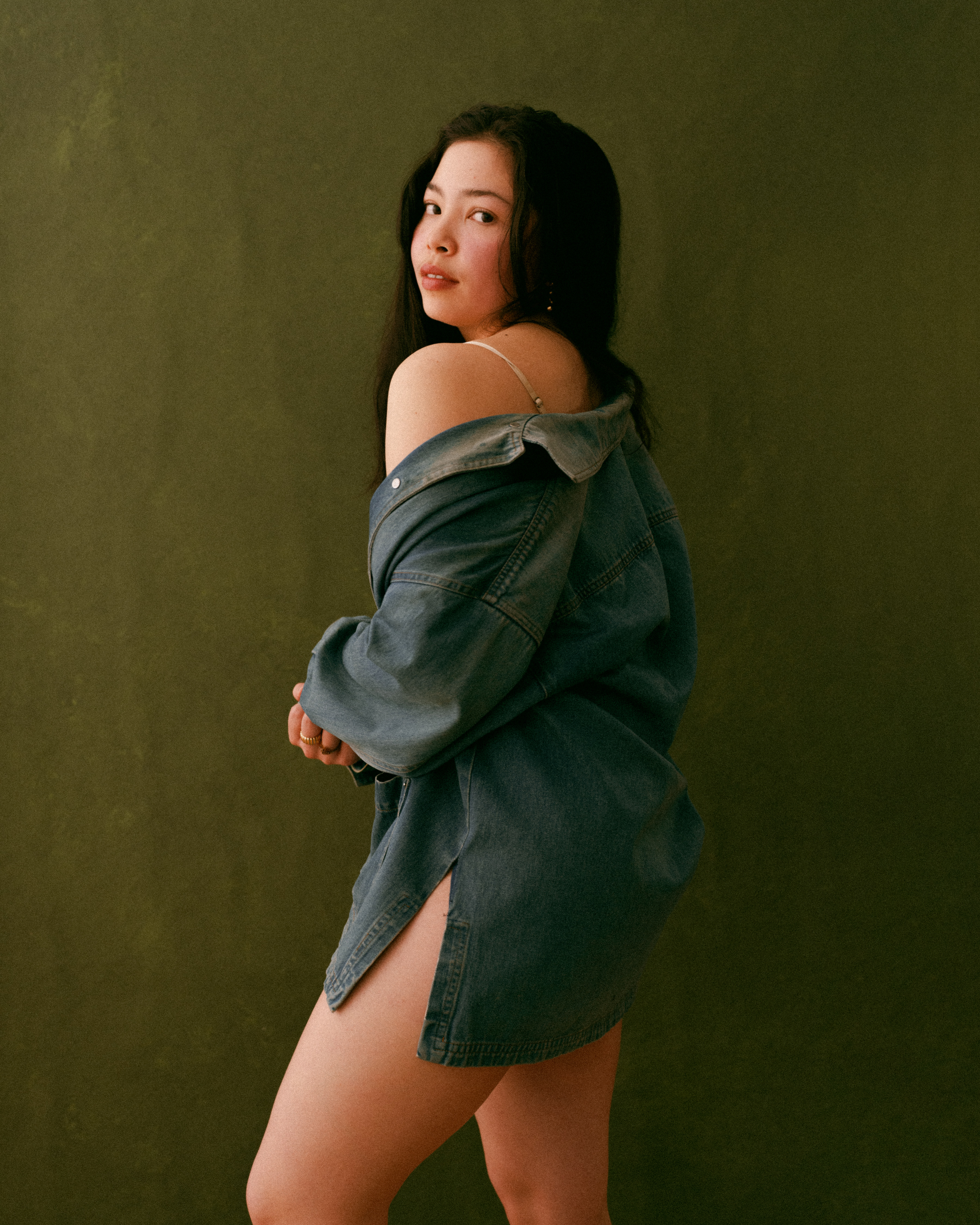 Me standing in front of a greeen background wearing a denim shirt